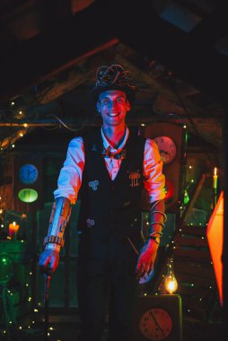 Steampunk takım elbiseli, silindir şapkalı, gözlüklü ve saat atölyesinde gülümseyen kamışlı mutlu bir erkek mucit.