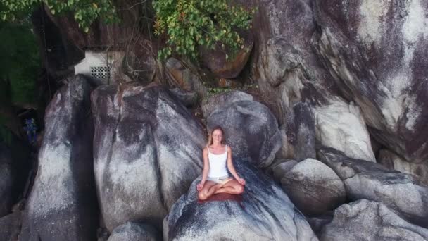 Εναέρια άποψη. Νεαρή γυναίκα κάθεται πάνω σε ένα βράχο και απολαμβάνοντας θέα στην κοιλάδα. Κορίτσι να κάθεται στη θέση του asana. — Αρχείο Βίντεο