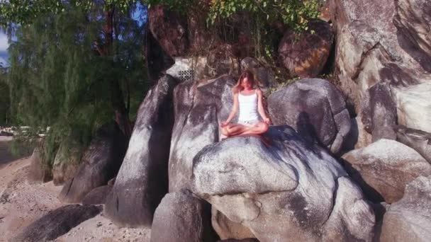 Vista aérea. Jovem mulher sentada em uma rocha e desfrutando de vista para o vale. Menina senta-se na posição asana . — Vídeo de Stock