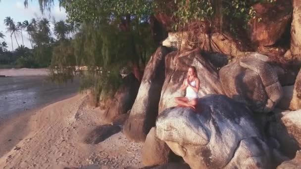Вид з повітря. Молода жінка сидить на скелі і насолоджується видом на долину. Дівчина сидить в позі Асани . — стокове відео