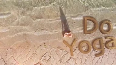 Kadın plajda yoga yapıyor.
