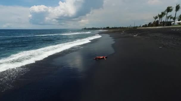 Mädchen am schwarzen Sandstrand von Bali — Stockvideo