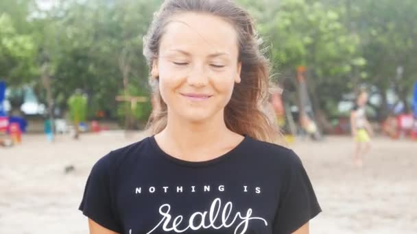 Жінка посміхається на пляжі під час заходу сонця — стокове відео