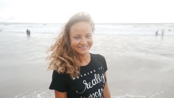 Жінка посміхається на пляжі під час заходу сонця — стокове відео