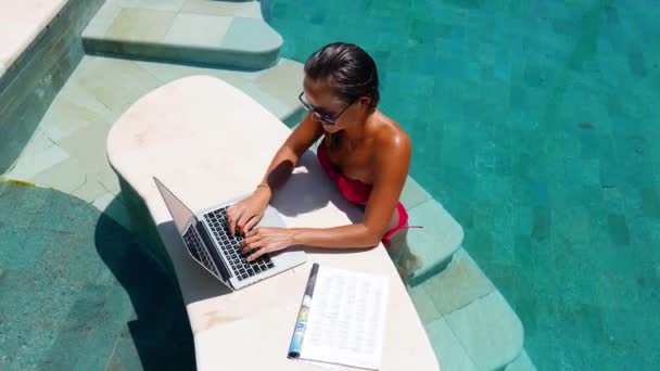 Femme travaillant sur ordinateur portable debout au bord de la piscine — Video