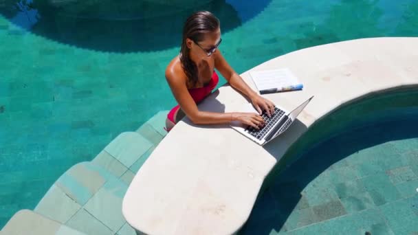 Mujer trabajando en el portátil de pie junto a la piscina — Vídeo de stock