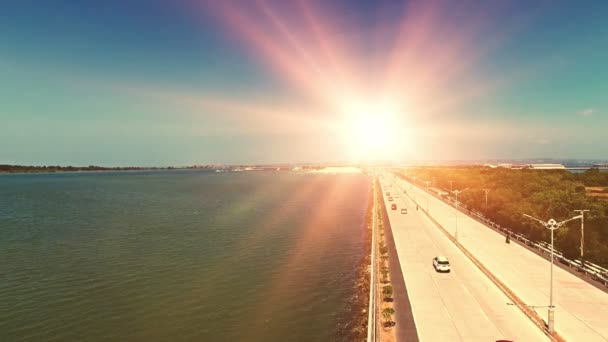 Autobahn und Verkehr entlang der Küste. Küstenautobahn mit fließenden Autos, wunderschönem türkisfarbenem Meerwasser, Inselsilhouette, kleiner Stadt und hohen Klippen bei sonnigem Tag mit blauem Himmel. — Stockvideo