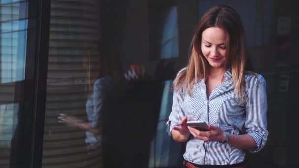 Vacker affärskvinna med mobil på bakgrund av businesscentret — Stockvideo