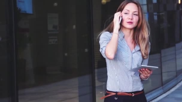 Красивая деловая женщина с мобильным телефоном на фоне бизнес-центра — стоковое видео