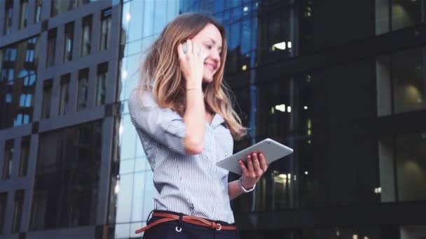 Красивая деловая женщина с мобильным телефоном на фоне бизнес-центра — стоковое видео