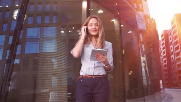 Businesswoman speaking over mobile phone and smilig to the sun. Beautiful lady holding important documents at her hand. — Stock Video