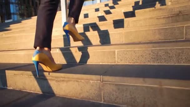 Movimento lento. Menina bonita nova em sapatos amarelos em saltos oi subindo as escadas. Vídeo em estilo cinematográfico. Vista em pernas e sapatos amarelo-azuis . — Vídeo de Stock