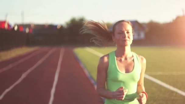 En cámara lenta. El aire caliente se evoca. Hermosa joven ejercicio de correr y correr en pista de atletismo en el estadio al amanecer. Video de estilo cinematográfico . — Vídeo de stock