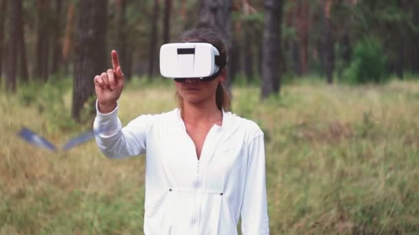 Mujer con auriculares VR mirando los objetos en realidad virtual. VR es una tecnología informática que simula una presencia física y permite al usuario interactuar con el entorno . — Vídeo de stock