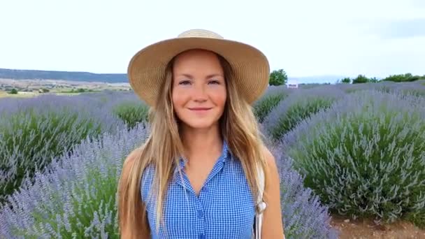 Närbild porträtt av ung vacker kvinna och lavendel fält på bakgrunden. Kvinna klädd i en hatt leende på våren. — Stockvideo