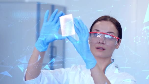 Žena hledající na futuristický displej s digitálními linkami a chemickými vzorci. Mladá žena v chráněných brýlích pracuje v laboratoři. — Stock video