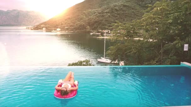 AERIAL. Woman lying on the air mattress at the Infinity swimming pool with fantastic sea and mountain view. — Stock Video