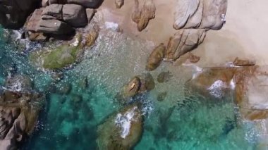 Denizde kayanın üzerinde yatan sarı bikinili, genç ve güzel bir model. Moda çekimi. Tayland adasında havadan çekilmiş bir video. Tatilde dinleniyorum.