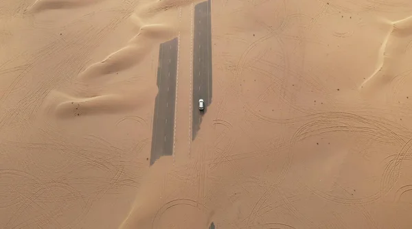 Вид сзади: волосатая женщина с желтым рюкзаком смотрит на песчаную дорогу после песчаной бури. Путешествия в пустыню. — стоковое фото