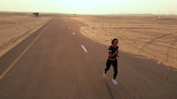 Νεαρή γυναίκα τρέχει σ 'ένα δρόμο στην έρημο — Φωτογραφία Αρχείου