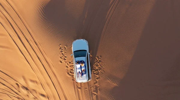 AERIAL. Vista superior do jovem casal relaxante no telhado de carros no deserto. — Fotografia de Stock