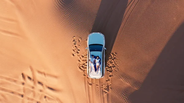 AERIAL. Вид сверху на молодую пару, отдыхающую на крыше автомобиля в пустыне. — стоковое фото