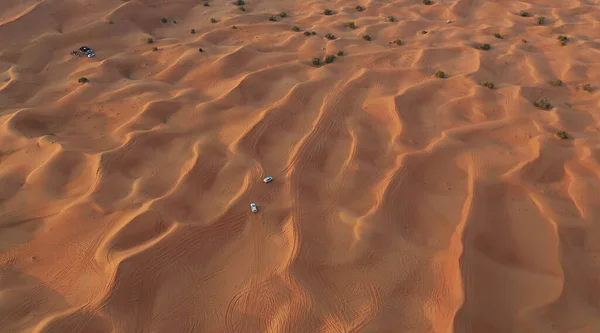 AERIALNE. Kolumna białych samochodów podróżujących po pustyni piasku. — Zdjęcie stockowe