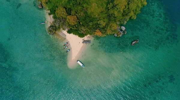 AERIAL. Вид сверху на зеленый остров и пляж с традиционной тайской лодкой на закате. — стоковое фото