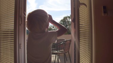 Çocuk pencereyi açar ve pencereden dışarı bakar. Evde kal ve karantina konseptini uygula. Salgın izolasyonu