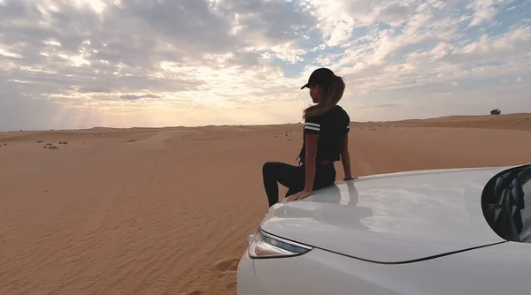 Una joven viajera sentada en el coche en el desierto. Concepto de viaje. — Foto de Stock