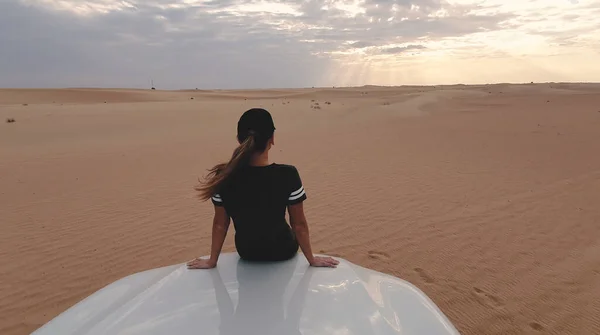 Jeune voyageuse assise sur la voiture dans le désert. Concept de voyage. — Photo