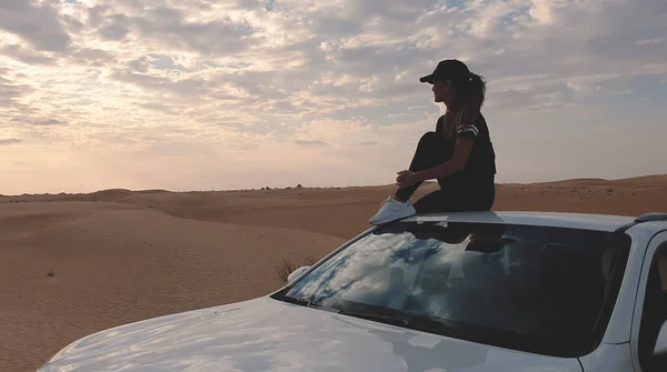 Young traveller woman sitting on the car in desert. Travel concept. — Stock Photo, Image