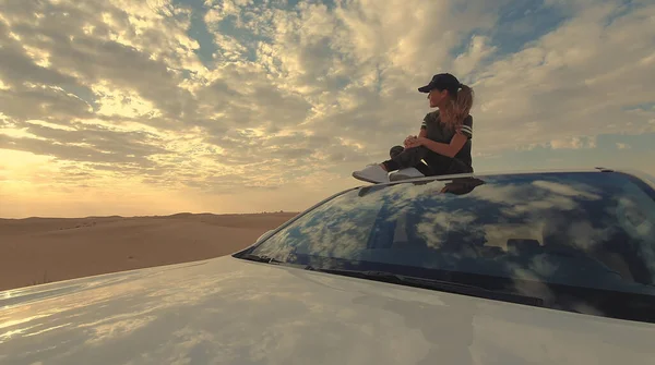 Jovem viajante sentada no carro no deserto. Conceito de viagem. — Fotografia de Stock