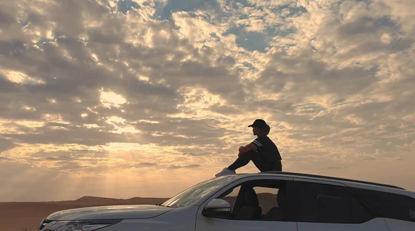Genç gezgin kadın çölde arabada oturuyor. Seyahat kavramı.