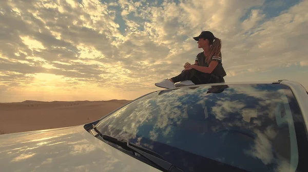 Jovem viajante sentada no carro no deserto. Conceito de viagem. — Fotografia de Stock