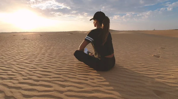 Silhouette of a young woman doing yoga at sunset in the vast desert. Epic sunset and sports concept photo.
