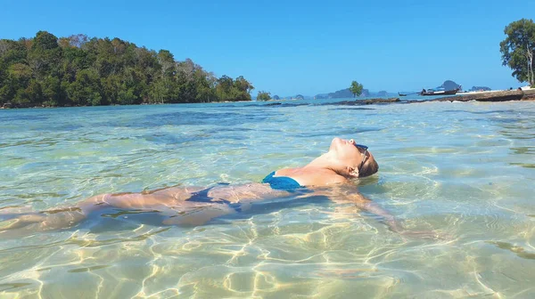 Une jeune femme allongée sur la plage. Modèle de mode posant sur une île tropicale en lunettes de soleil. — Photo