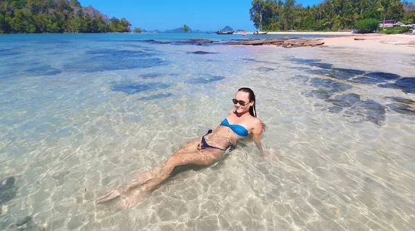 Une jeune femme allongée sur la plage. Modèle de mode posant sur une île tropicale en lunettes de soleil. — Photo