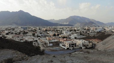 AERİAL. Arkadaki kadın BAE 'deki geleneksel kasabanın fotoğrafını çekmek için cep telefonu kullanıyor.