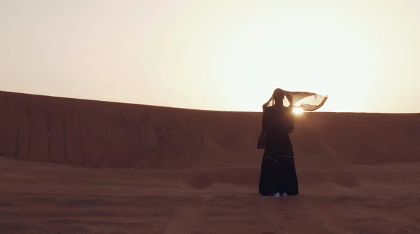 Πορτρέτο μιας νεαρής Άραβας που φοράει παραδοσιακά μαύρα ρούχα κατά τη διάρκεια του όμορφου ηλιοβασιλέματος πάνω από την έρημο. — Φωτογραφία Αρχείου