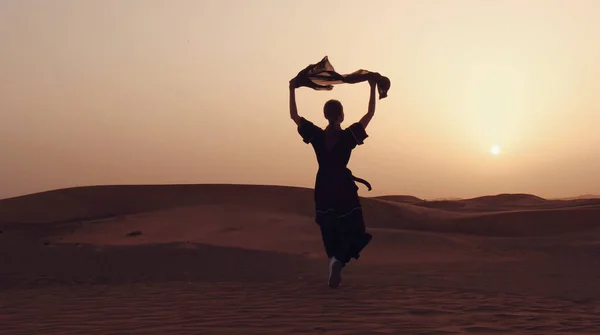 Retrato de una joven árabe vestida con ropa negra tradicional durante el hermoso atardecer sobre el desierto. — Foto de Stock