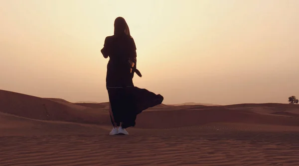 Πορτρέτο μιας νεαρής Άραβας που φοράει παραδοσιακά μαύρα ρούχα κατά τη διάρκεια του όμορφου ηλιοβασιλέματος πάνω από την έρημο. — Φωτογραφία Αρχείου