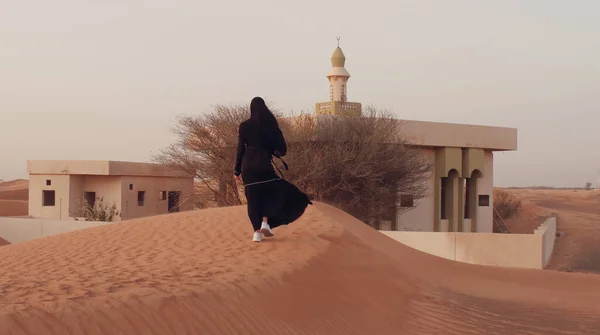 Retrato de una joven árabe vestida con ropa negra tradicional durante el hermoso atardecer sobre el desierto. — Foto de Stock