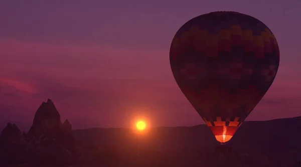 Erstaunlich himmlischer Hintergrund - riesiger, bunter Heißluftballon fliegt in den glühenden Himmel des Sonnenuntergangs — Stockfoto