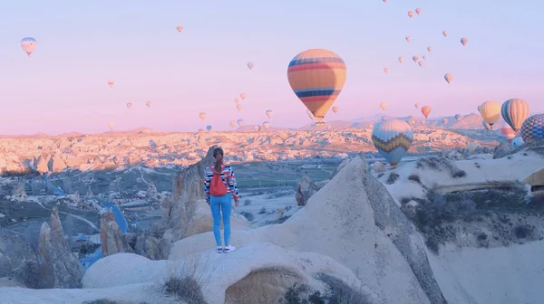 Női utazó hátizsákkal, aki a léggömböket nézi. Sportos lány és sok hőlégballon. A teljes szabadság, teljesítmény, teljesítmény, boldogság érzése — Stock Fotó