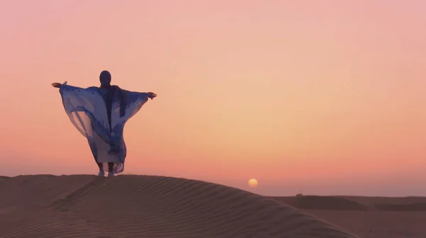 Retrato da bela mulher árabe vestida em azul vestido tradicional no deserto durante o pôr do sol. — Fotografia de Stock