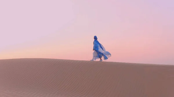 Retrato da bela mulher árabe vestida em azul vestido tradicional no deserto durante o pôr do sol. — Fotografia de Stock