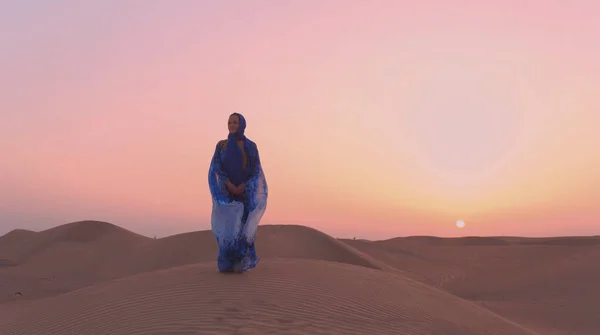 Retrato da bela mulher árabe vestida em azul vestido tradicional no deserto durante o pôr do sol. — Fotografia de Stock