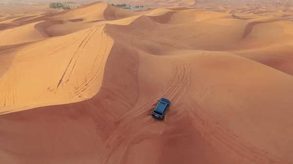 AERIAL. Vuelo de altura por encima del coche. Desierto safari coche arena corriendo en el desierto de Dubai durante la puesta del sol — Foto de Stock