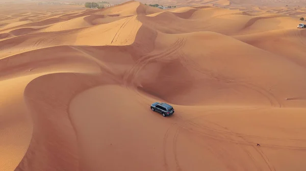 AERIAL. Vuelo de altura por encima del coche. Desierto safari coche arena corriendo en el desierto de Dubai durante la puesta del sol — Foto de Stock